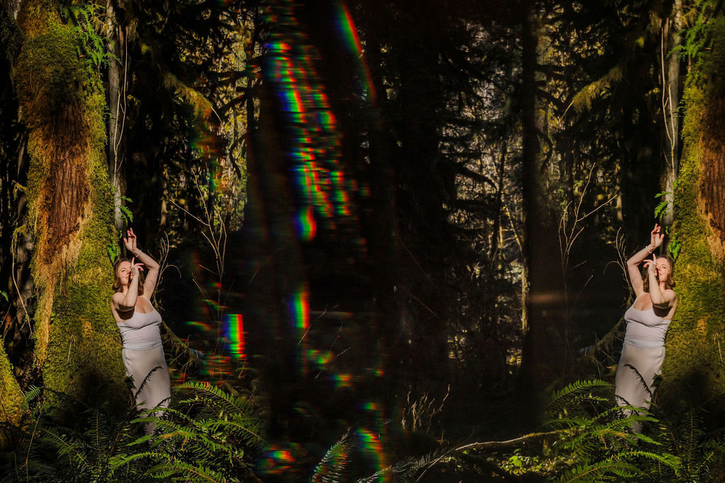 Angela Bolton mirrored twice in a mossy forest, hands raised in prayer, a column of rainbow light between them