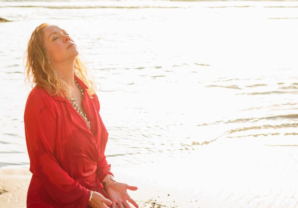 Open hands resting on wet sand at the edge of a sunlit tide